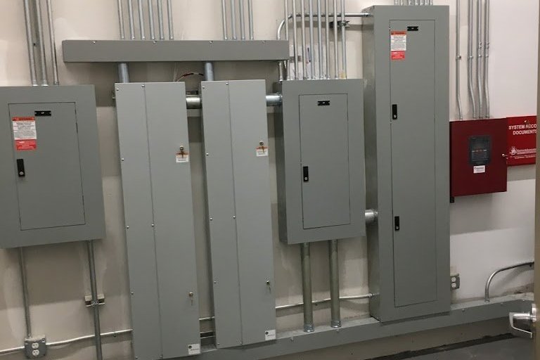 Commercial electrical room with panelboards, neatly run EMT conduit and a fire alarm control panel